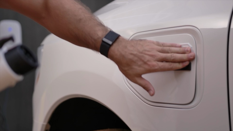 A driver opening the charge port of an electric truck